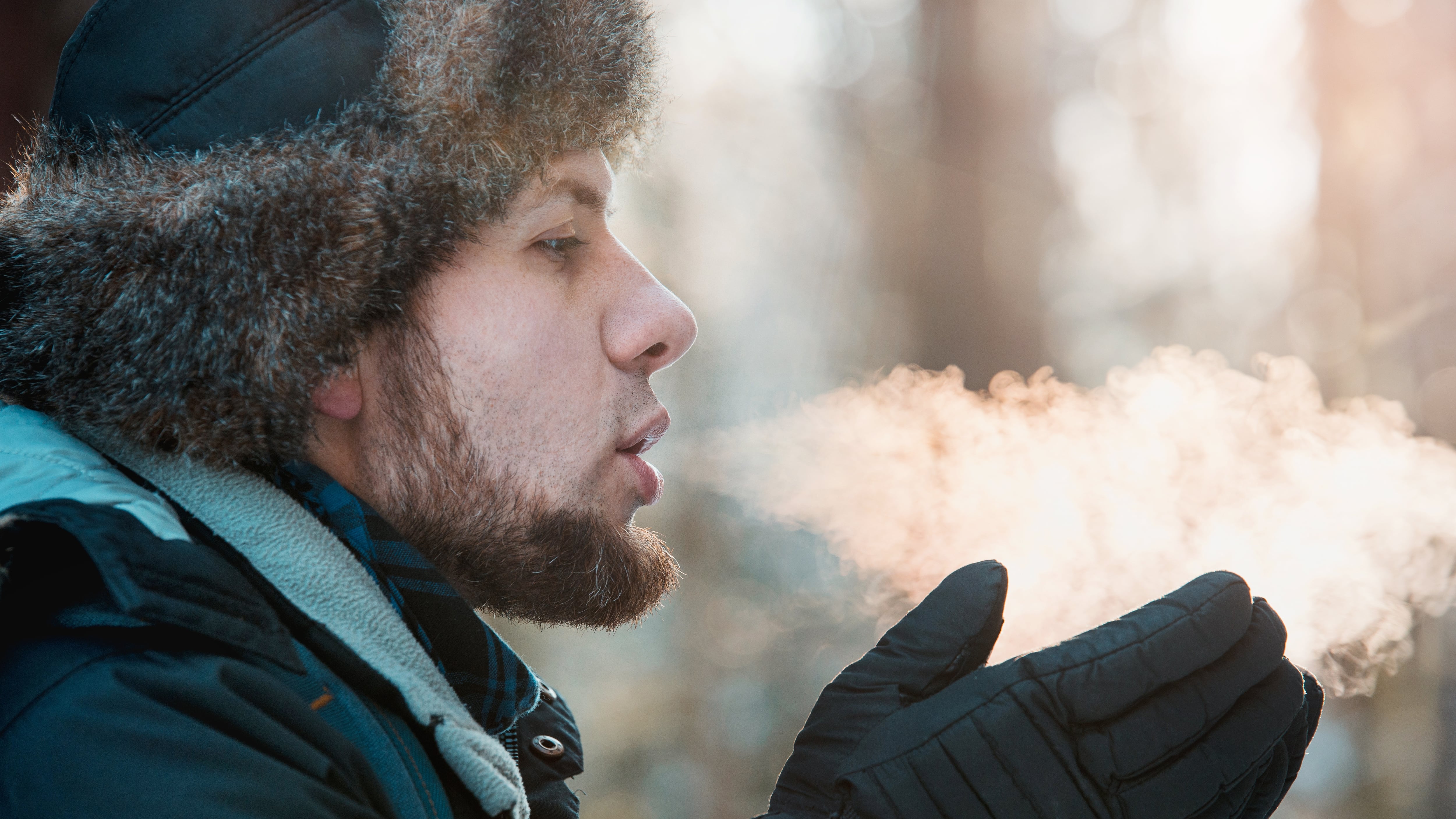A man blowing air on gloves during the winter.