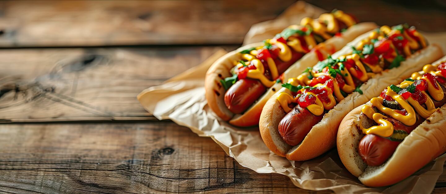 Two hot dogs with ketchup and mustard on parchment paper.