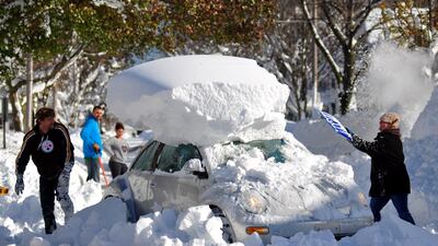BUFFALO, NY - NOVEMBER 21: Michael Palmer and Carin Schultz work to clear her car of snow and remove it from Union street on November 20, 2014 in the suburb of Hamburg, Buffalo, New York. The record setting Lake effect snowstorm dumped up to six feet of snow in less than 24 hours closing a one hundred mile section of The New York State Thruway as well as other major roads around Buffalo. Twelve deaths have already been attributed to the storm and with warming temperatures and rainfall in the forecast epic flooding is expected. (Photo by John Normile/Getty Images)