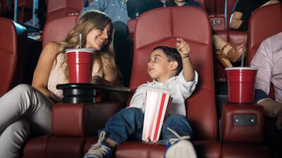 Kid sitting in the cinema theater with his parents and getting excited about the movie